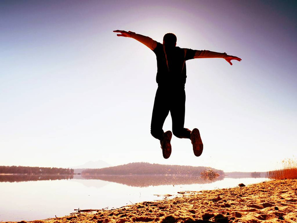 Mann verrückt springen am Strand. Sportler fliegt am Strand während des Sonnenaufgangs über dem Horizont - Foto, Bild