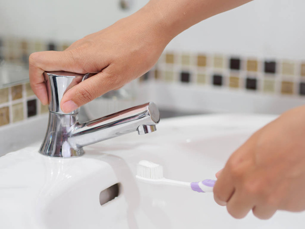 Zbliżenie kobieta ręce trzyma szczoteczkę do zębów z pasty do zębów w łazience umywalka, stomatologicznych opieki zdrowotnej. - Zdjęcie, obraz