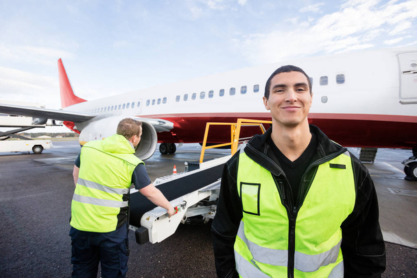 Worker Smiling While Colleague Working On Runway - 写真・画像
