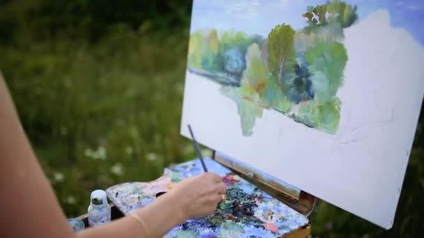 Güneşli yaz günde ekose parkta oturan ve beraberlik resim tarafından suluboya boya güzel bir manzara bitirme büyüleyici kadın - Video, Çekim