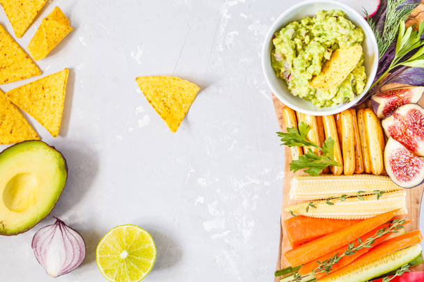 guacamole with vegetables and snacks on a wooden board - Photo, Image