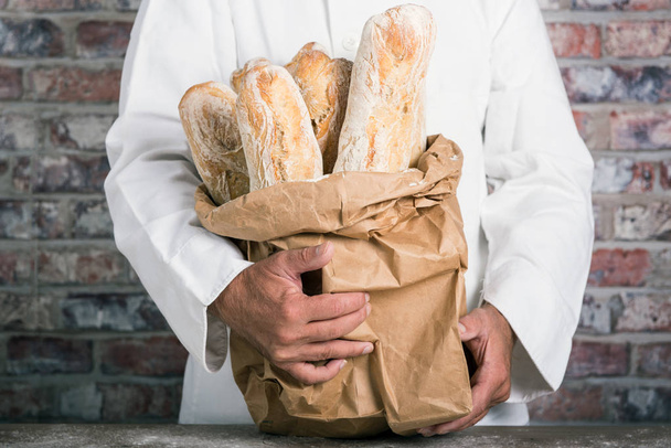 パン屋の伝統的なパンを保持しているフランスのバゲット - 写真・画像