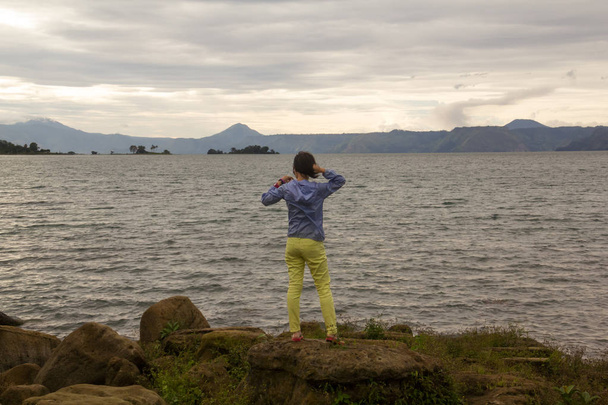 woman standing on rock looking at the lake toba - Photo, Image