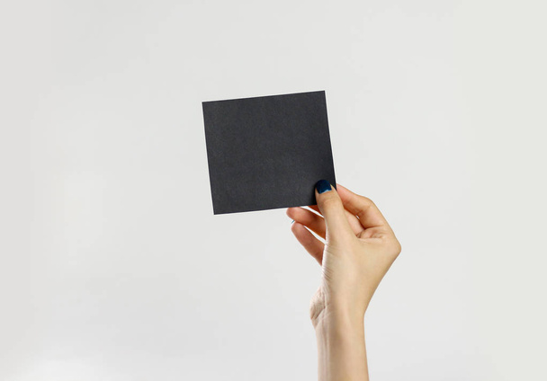 Female hands holding a black sheet of paper. Isolated on gray ba - Fotó, kép