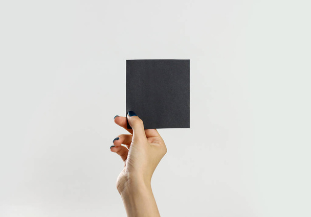 Female hands holding a black sheet of paper. Isolated on gray ba - Foto, Bild
