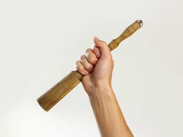 Male hands holding a wooden pestle. Isolated on gray background. - Photo, Image