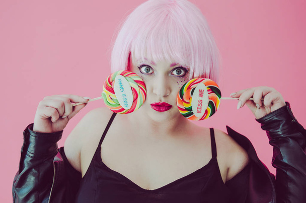 sensual woman with pink hair holding lollypops - 写真・画像