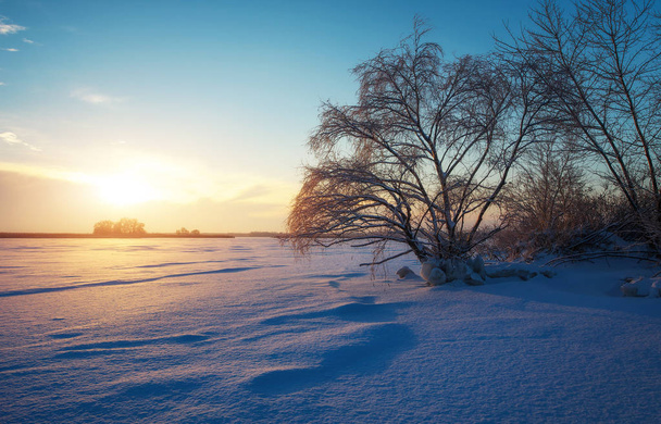 Gyönyörű téli táj, a befagyott tó, fák és napnyugtakor ég - Fotó, kép
