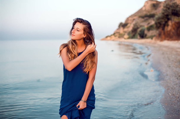 Model in blauem Kleid posiert am Strand  - Foto, Bild