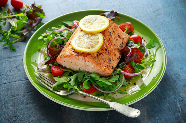 Baked salmon steak with tomato, onion, mix of green leaves salad in a plate. healthy food - Photo, Image