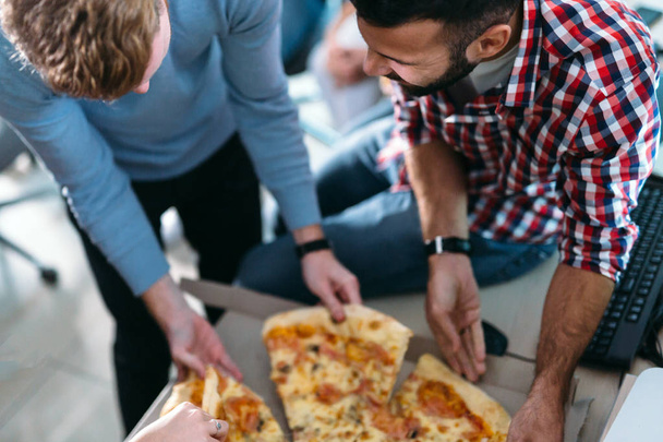 Software enginneers sharing pizza on break from work in their company - Foto, Imagen