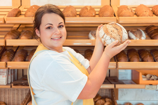 Saleslady in bakery shop presenting bread - Photo, Image