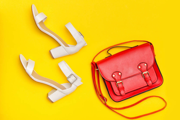 Fashionable concept. Red handbag and white shoes. Yellow background, top view - 写真・画像