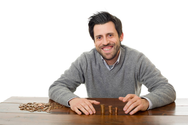 El hombre examina las monedas en un escritorio, aislado
  - Foto, Imagen