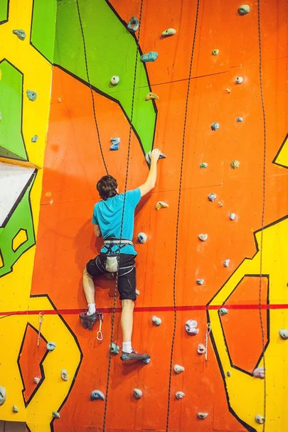 Man climber on artificial climbing wall in bouldering gym. - 写真・画像