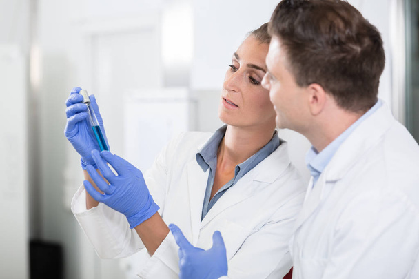 Scienziati in laboratorio che guardano il liquido blu in fiala
 - Foto, immagini