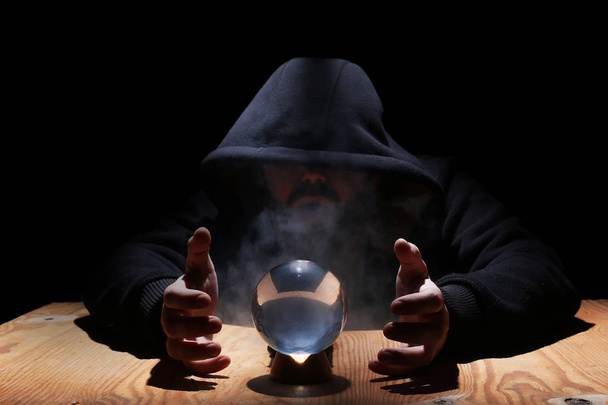 hombre en una capucha negra con bola de cristal
 - Foto, imagen