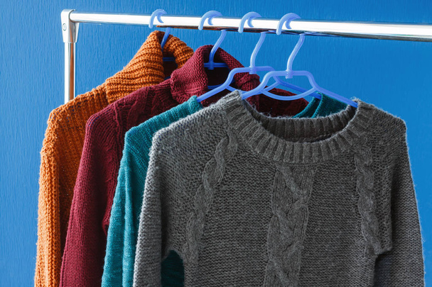 Warm woolen sweaters hanging on hangers - Foto, Imagen