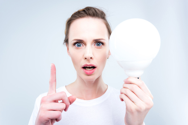 woman with light bulb pointing up - Φωτογραφία, εικόνα