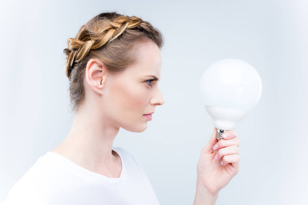 focused woman with light bulb - Фото, изображение