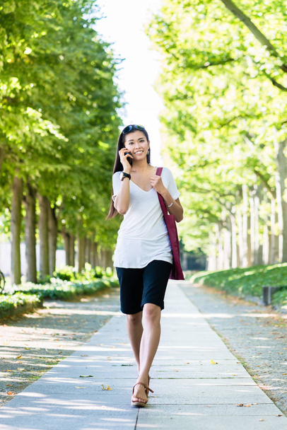 Азіатський жінка говорити на мобільний телефон на відкритому повітрі - Фото, зображення
