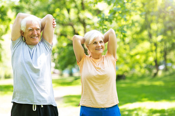 Senior Couple Exercising In Park - Foto, imagen