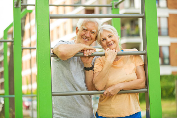Senior couple exercising at outdoor gym - Photo, Image