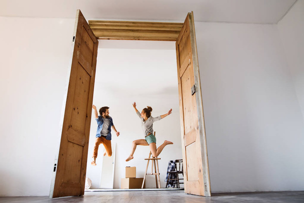 Young couple moving in a new house, jumping up high. - Foto, afbeelding