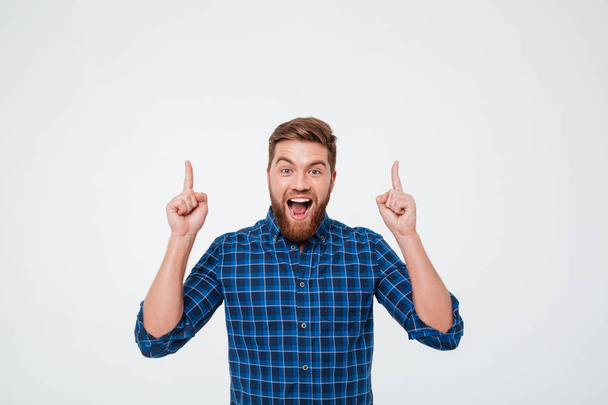 Happy bearded man in checkered shirt pointing up - Fotoğraf, Görsel