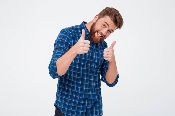 Smiling bearded man in checkered shirt showing thumbs up - Fotó, kép