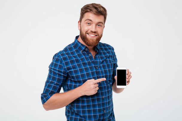 Smiling Bearded man in checkered shirt showing blank smartphone screen - Foto, immagini