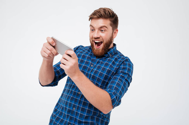 Happy bearded man in checkered shirt playing on his smartphone - Фото, зображення