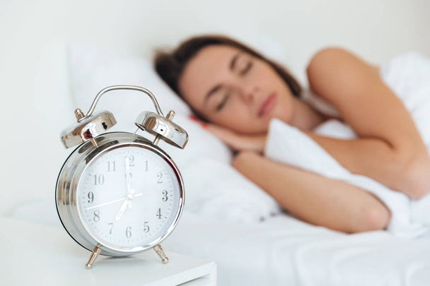 Close up portrait of an alarm clock with sleeping woman - Zdjęcie, obraz