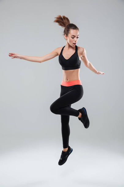 Full length image of a sports woman jumping in studio - 写真・画像