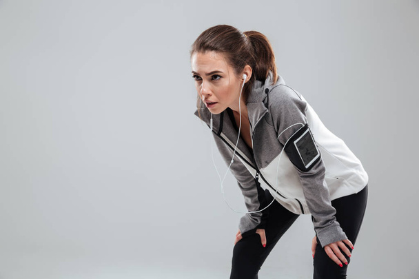 Tired female runner in warm clothes in studio - Foto, afbeelding