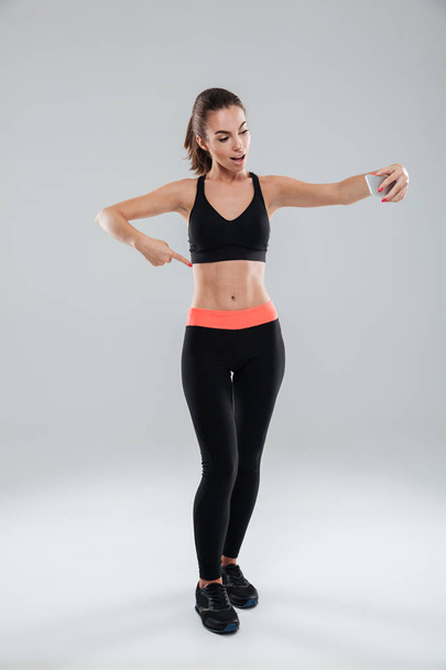 Full length picture of happy fitness woman pointing at abdominals - Fotó, kép