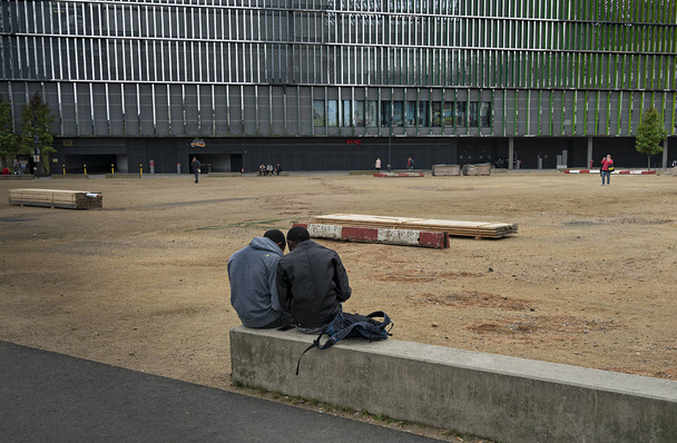 Dos hombres sentados en un bloque de piedra en la gran ciudad
   - Foto, imagen