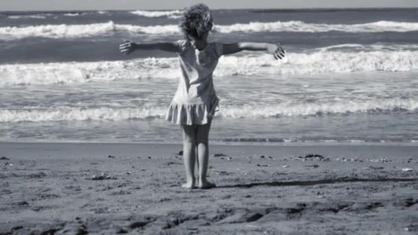 Käsite vapaus, pieni tyttö avosylin edessä valtameren isoja aaltoja, hidastettuna, musta ja valkoinen - Materiaali, video
