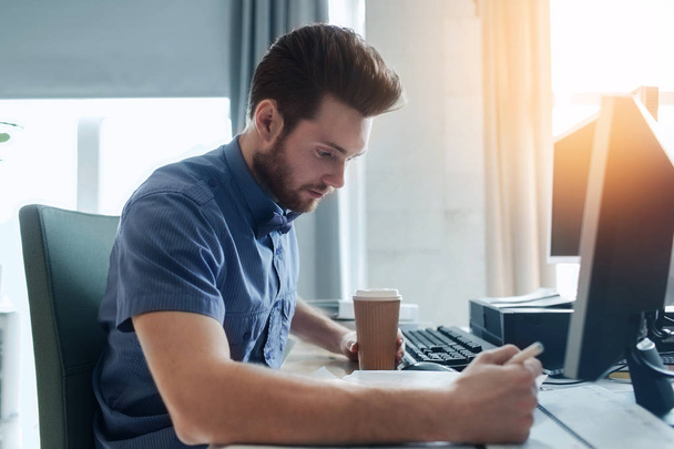 creative male office worker with coffee writing - Valokuva, kuva