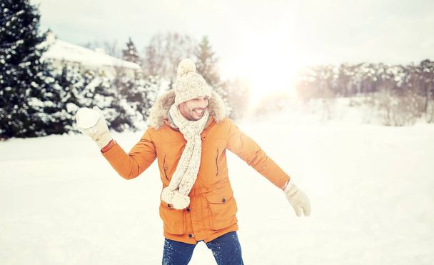 szczęśliwy młody mężczyzna gry śnieżkami w zimie - Zdjęcie, obraz