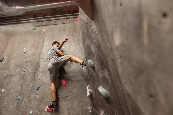 young man exercising at indoor climbing gym wall - 写真・画像