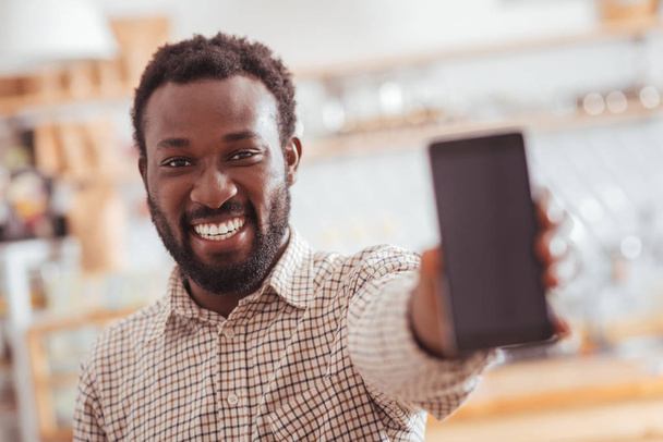 Joyful man showing his new phone in coffeehouse - Фото, зображення
