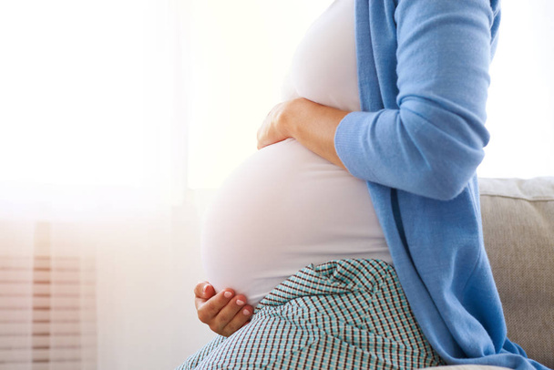 Pregnant woman holding hands on her belly - Foto, Imagem