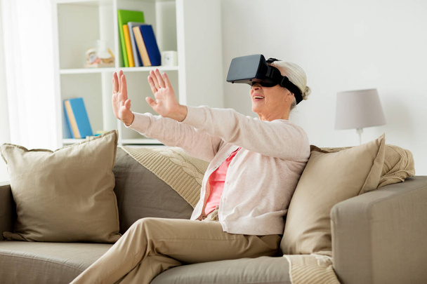 old woman in virtual reality headset or 3d glasses - 写真・画像