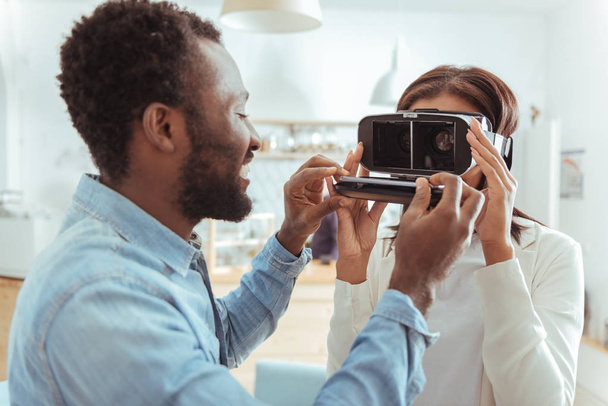 Smiling man inserting smartphone into her friends VR headset - Foto, Imagen