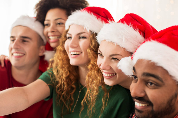 happy friends in santa hats at christmas party - Foto, Imagen