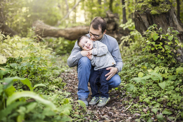 Little boy and his father on grass in autumn forest - 写真・画像