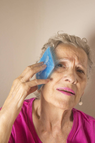 Senior vrouw met ijs op hoofd voor hoofdpijn - Foto, afbeelding