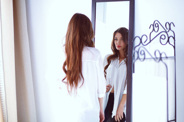 Young woman looking herself reflection in mirror at home. Young woman. - Fotó, kép