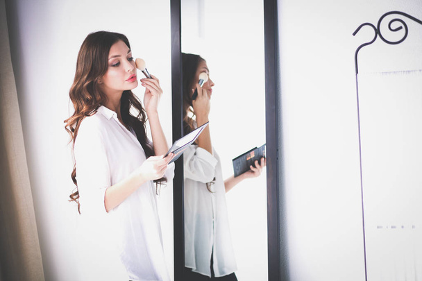 Young woman looking herself reflection in mirror at home. Young woman. - 写真・画像